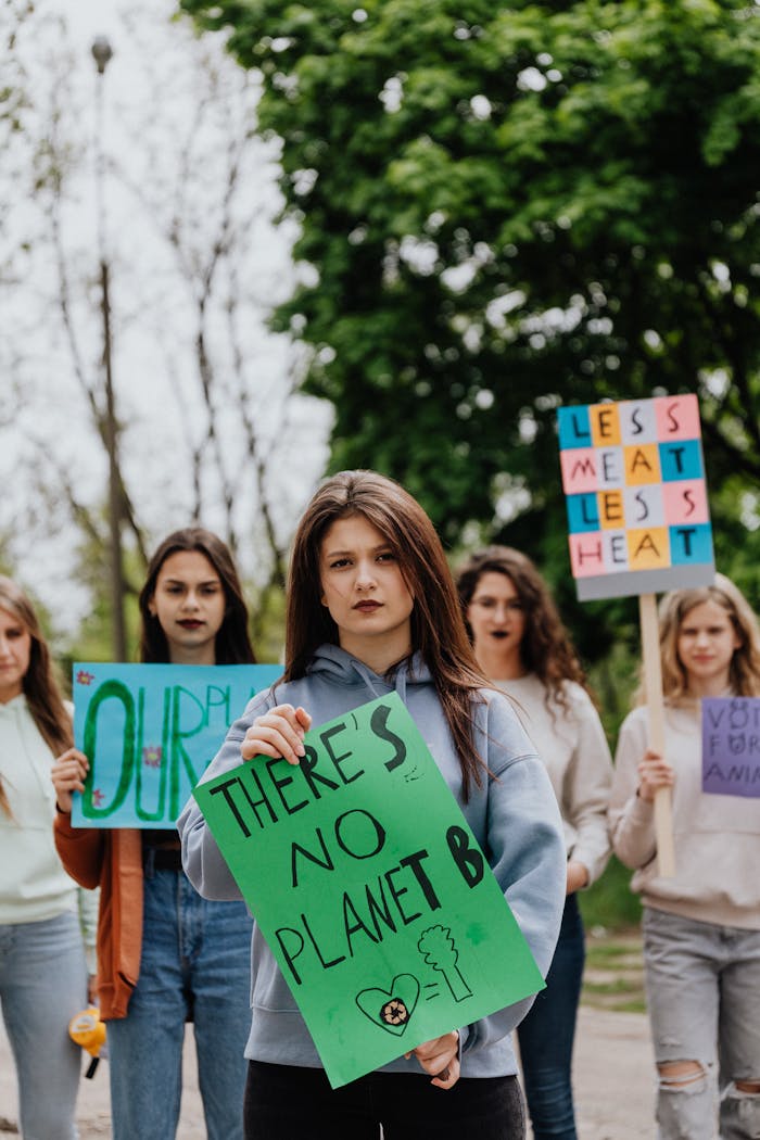 Young women protesting for environmental change, holding vibrant signs outdoors.